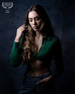 Mulher de cabelos longos e blusa verde em pose contemplativa. No topo, selo Portrait Photo Awards e autoria de Jesus Lopes