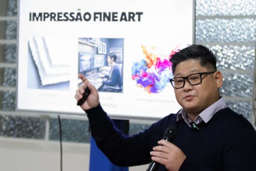 Homem palestrando com microfone em frente a uma tela com o título Impressão Fine Art