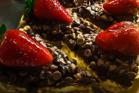 Fatias de torta de chocolate cobertas com gotas de chocolate e morangos inteiros