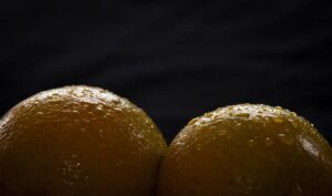 Duas laranjas com gotas de água na casca em um fundo escuro