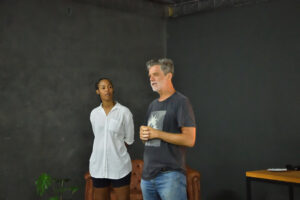Homem e mulher em pé conversando em um ambiente com paredes cinza-escuras